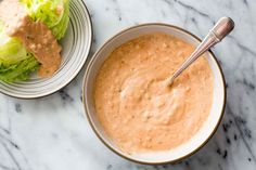 two bowls filled with food sitting on top of a marble counter next to a bowl of lettuce