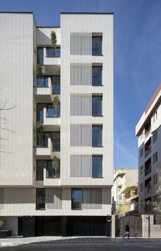 an apartment building with vertical striped facade and balconies on the upper floor is shown