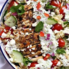 a salad with chicken, cucumber, tomatoes and feta cheese in a bowl