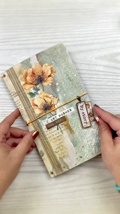 two hands holding an open book with flowers on it