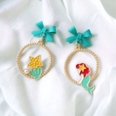 Little Mermaid Earrings Set. Features Cartoon Mermaid And Starfish Estimated 1.5” Pendant Hangs From A Blue Bow. For Pierced Ears. Gold Tone. #Littlemermaid #Littlemermaidearrings #Mermaid #Mermaidearrings #Earrings #Disneyearrings 12212301 Whimsical Blue Earrings For Party, Whimsical Blue Jewelry For Parties, Whimsical Blue Round Jewelry, Whimsical Round Blue Jewelry, Cute Blue Round Jewelry, Cartoon Mermaid, Disney Earrings, Mermaid Earrings, Blue Bow