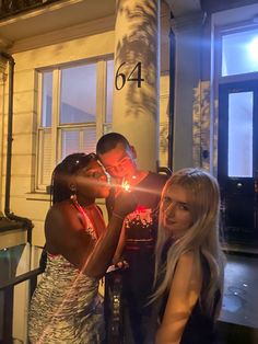 two women and a man standing next to each other holding sparklers in their hands