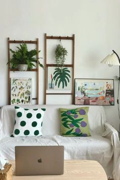 a living room with white couches and plants on the wall above it, along with a laptop