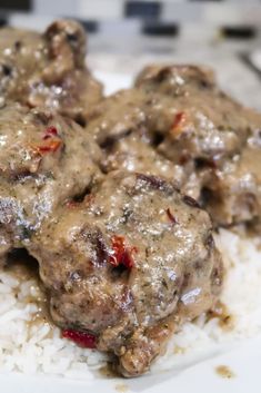 two meatballs covered in gravy on top of white rice with red peppers