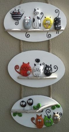 three white surfboards with cats on them hanging from the wall and two are holding magnets