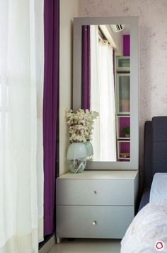 a bedroom with a dresser, mirror and flowers in the vase on top of it