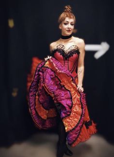 a woman in a red and purple dress posing for the camera with her hands on her hips