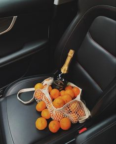 oranges and a bottle in a mesh bag on the back seat of a car