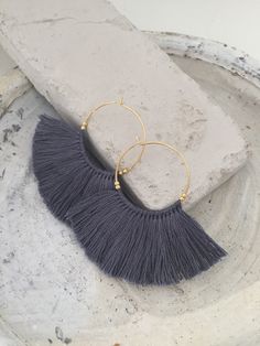 a pair of earrings with tassels sitting on top of a white plate next to a