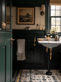 a bathroom with black and white tile flooring, green walls and gold trimming