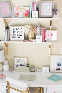 a white desk topped with lots of shelves filled with books and office supplies next to a lamp