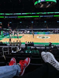 people sitting in the bleachers at a basketball game with their feet on the floor