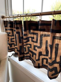 the curtains are hanging on the window sill in the room that is decorated with black and brown designs