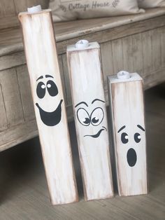 three wooden sticks with faces painted on them sitting next to each other in front of a bed