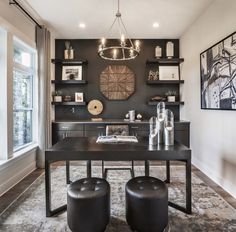 a dining room table with two stools in front of it and shelves on the wall