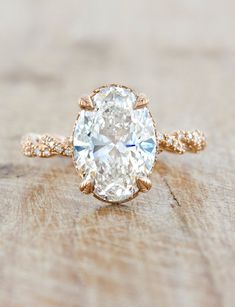 an oval cut diamond ring on top of a wooden table