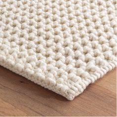 a close up view of a white rug on a wooden floor, with the top part of the rug visible