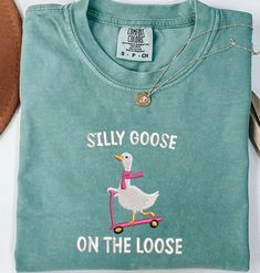 Comfort Colors Embroidered Shirt Silly Goose On the Loose Tshirt Goose Crewneck Shirt Silly Goose T-Shirt Funny Shirt Gift,  MADE IN USA PLEASE NOTE THAT THE PICTURES ON THE LISTING ARE SAMPLES ONLY. If interested in adding embroidery to the sleeve please go to this listing: https://www.etsy.com/listing/1674502020 Because it is made to order, we don't accept the return or exchange unless we make a mistake We are unable to replace or refund purchases based on the color and the font selections. Pl Green Casual T-shirt With Embroidered Text, Casual Green T-shirt With Embroidered Text, Casual Green Tops With Embroidered Graphics, Casual Green Top With Embroidered Graphics, Casual Cotton Shirt With Embroidered Text, Embroidered Crew Neck Graphic Tee Shirt, Casual Crew Neck Shirt With Embroidered Text, Graphic Tee Shirt With Embroidered Graphics And Crew Neck, Graphic Tee With Embroidered Graphics And Crew Neck