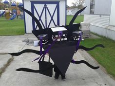 a person standing in front of a black kite with purple ribbons and decorations on it