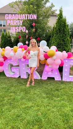 a woman standing in front of a sign with balloons