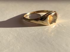 a gold ring sitting on top of a white table next to a shadow from the sun