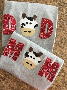 two towels with the letters dn and a cow on them are sitting next to each other