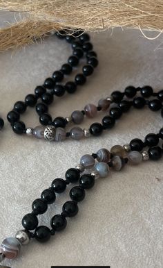 Mala in Obsidian and Botswana Agate with Buddha A mala, also known as a prayer bead, is a traditional tool used for meditation and prayer, often in Hinduism, Buddhism, and other spiritual practices. When crafted with specific stones, such as Obsidian and Botswana Agate, and adorned with a Buddha charm, the mala can hold unique significance and benefits. Obsidian Obsidian is a powerful volcanic glass known for its protective qualities. It is believed to shield against negativity, grounding the wearer and providing a sense of stability. Obsidian is also thought to reveal truths, bringing clarity and insight into one's life. It is often used to help release emotional blockages and facilitate deep healing. Botswana Agate Botswana Agate is a beautiful stone with banded patterns, prized for its Pieces Zodiac, Soothing Nature, Peace And Balance, Deep Healing, Yoga Mala, Botswana Agate, Virgo And Libra, Sagittarius And Capricorn, Capricorn And Aquarius