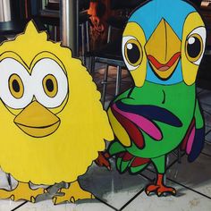 two cardboard cut outs of cartoon characters sitting on tiled flooring next to each other