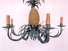 a pineapple hanging from a chandelier with five candles on each candle holder