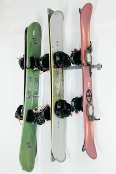 two snowboards mounted to the side of a white wall next to each other,