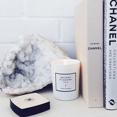 a white candle sitting next to a book on top of a table in front of a pile of books