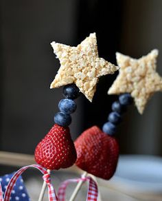 patriotic treats on sticks with strawberries and blueberries in the shape of stars are ready to be eaten