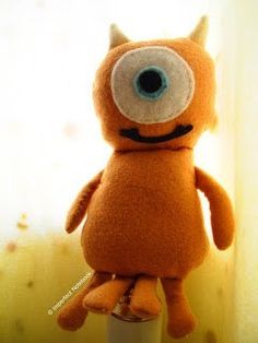 an orange stuffed animal with big eyes on top of a white pole in front of a window