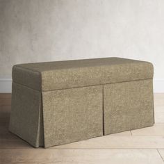 a large beige storage bench sitting on top of a hard wood floor next to a white wall