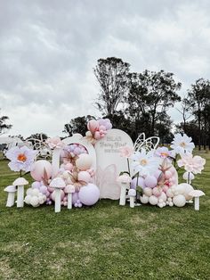 a bunch of balloons that are on the ground in front of a sign with flowers