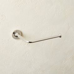 a white toilet paper roll holder on the wall with a metal bar attached to it