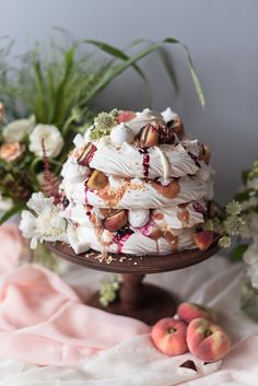 there is a cake on the table with flowers in the background and two peaches next to it