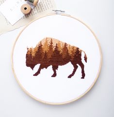 a cross stitch bison with trees in the background