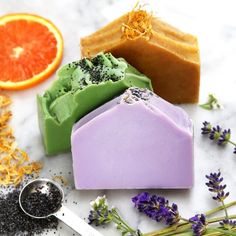 three soap bars sitting on top of each other next to orange slices and lavenders