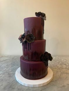 a three tiered cake with purple icing and flowers