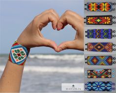 a person making a heart shape with their hands and bracelets in front of the ocean