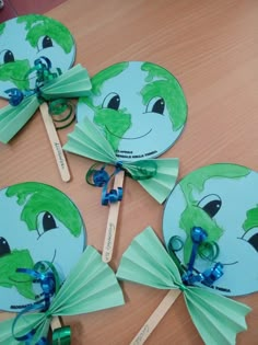 four paper fans with green faces and blue bows are on a table next to toothbrushes