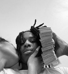 a black and white photo of a woman covering her face with stacks of papers