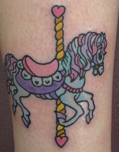 a colorful unicorn tattoo on the leg of a woman's leg, with a pink heart