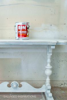 a can of paint sitting on top of a white table next to a wooden shelf