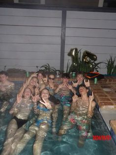 a group of people are in the water with their hands up and posing for a photo