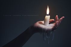 a person holding a candle in their hand with water dripping from the top and bottom