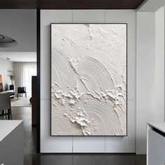 a large white painting hanging on the side of a wall next to a dining room table