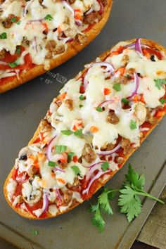 two pizzas with meat, cheese and vegetables on a baking sheet