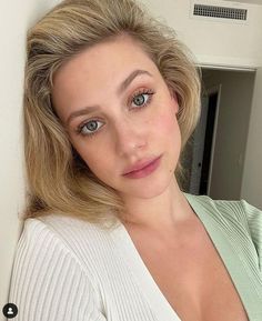 a woman is posing for a selfie with her hair pulled back and blue eyes